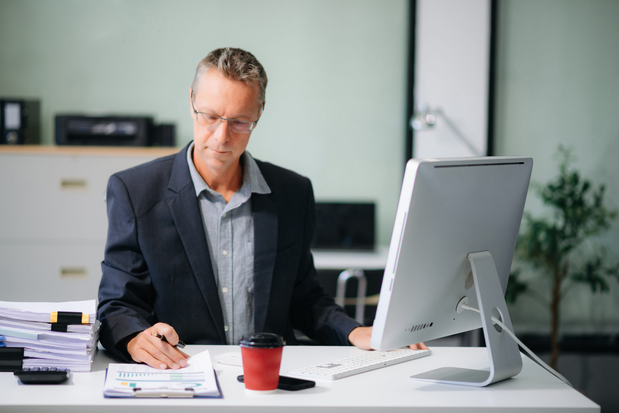 Mature business man executive manager looking at laptop watching online webinar training or having virtual meeting video conference doing market research working in office.